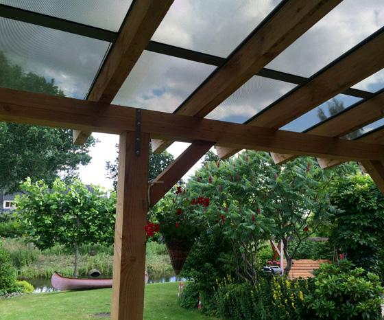 Houten veranda met geïntegreerde zonnepanelen in het dak, tuinproject van In ’t Hout Sierconstructies